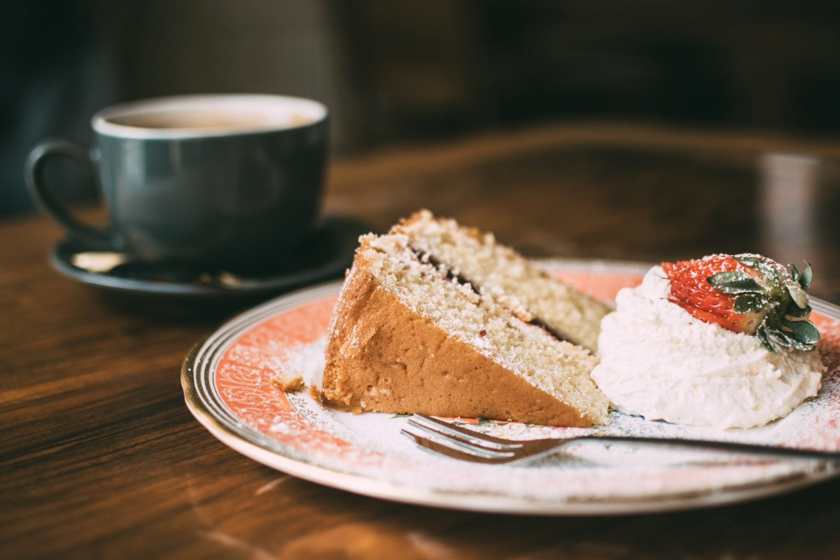 A slice of homemade cake with cream and a cup of coffee